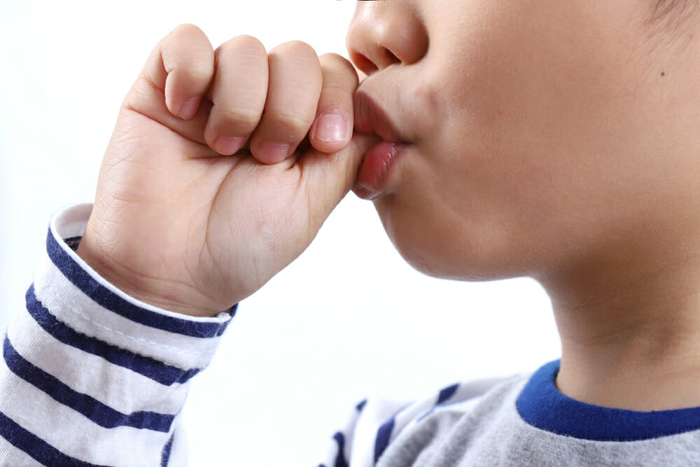 Why do children keep their fingers crossed and how do you help older children stop thumbing?